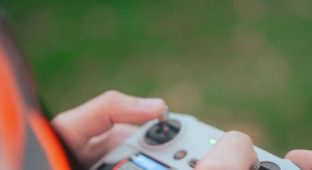 Télépilote en gilet orange tenant une radiocommande de drone